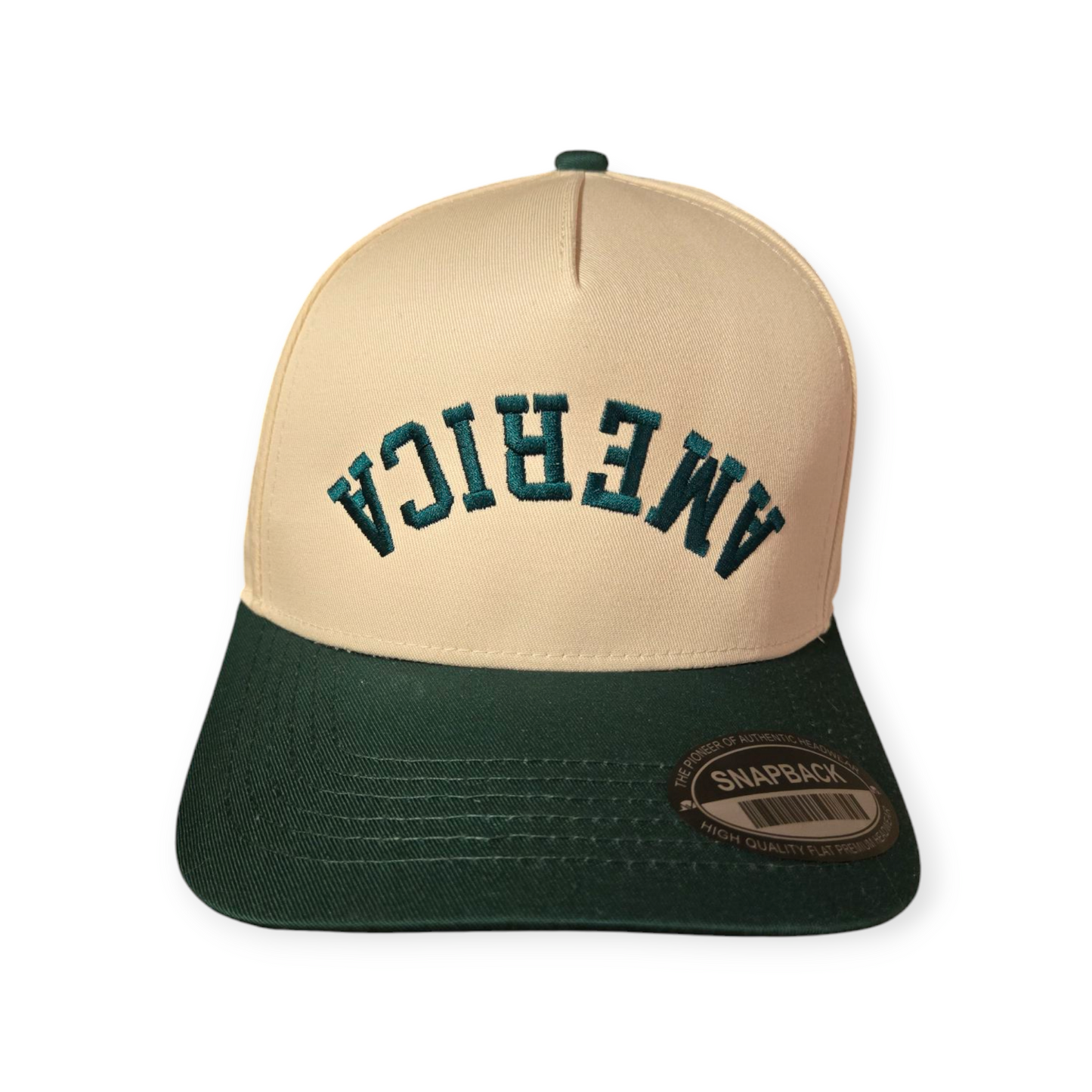 Front facing America Upside Down V1 structured hat in dark green and beige with the word “America” embroidered upside down in dark green on the front.