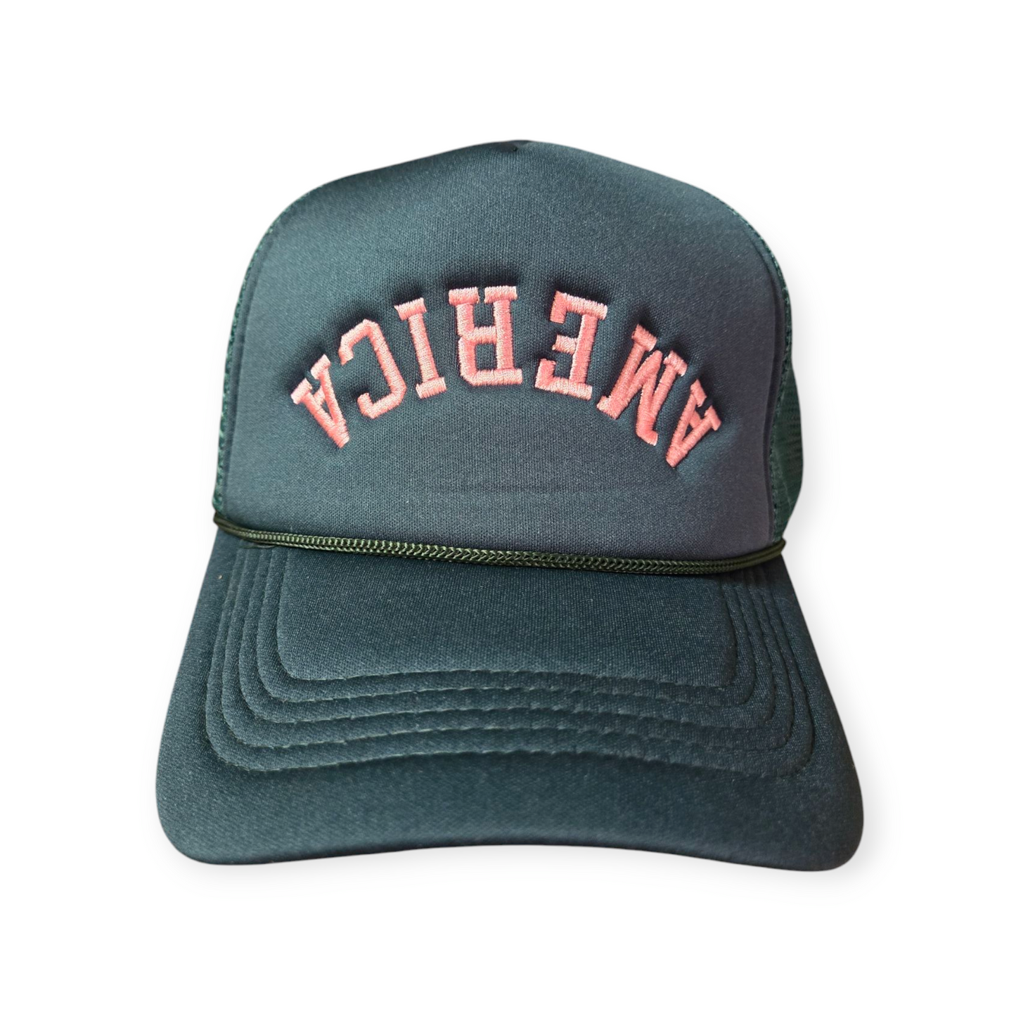 Front facing America Upside Down V1 trucker hat in forest green with the word “America” embroidered upside down in pink on the front.
