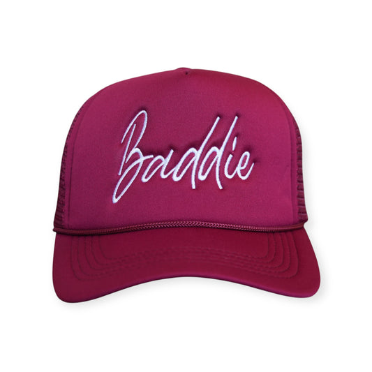 This is a Baddie V1 trucker hat in burgundy with a white embroidered design on the front panel, facing forward.