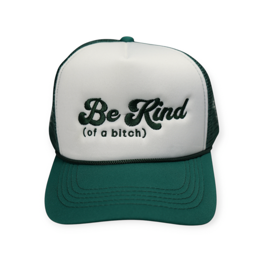 Front-facing forest green and white trucker hat with a curved brim and mesh back, featuring “Be Kind (Of A Bitch)” embroidered in forest green across the front.