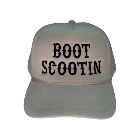 Front-facing white Boot Scootin trucker hat with a curved brim and mesh back, featuring “Boot Scootin” embroidered in black across the front.