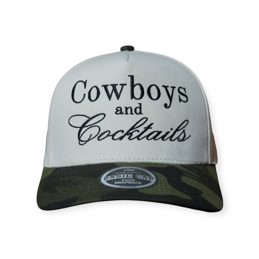 Camo and beige structured snapback hat with “Cowboys and Cocktails” embroidered across the front in black thread.