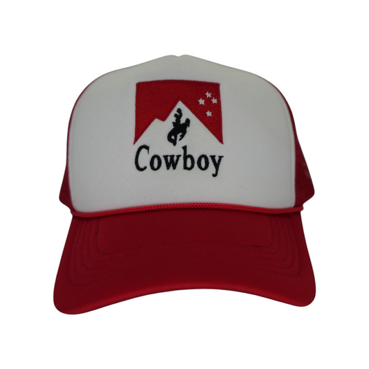 Front-facing red and white trucker snapback hat with a red cowboy riding a bucking horse design and black “Cowboy” lettering embroidered underneath.