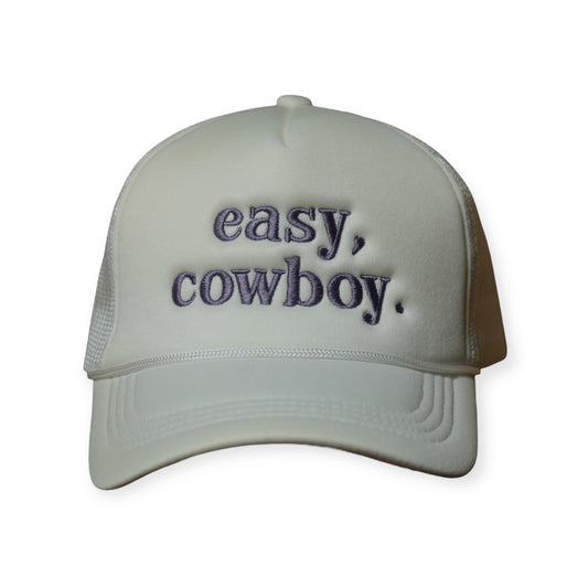White polyester trucker snapback hat with a curved brim and “EASY COWBOY” embroidered across the front in light purple thread.