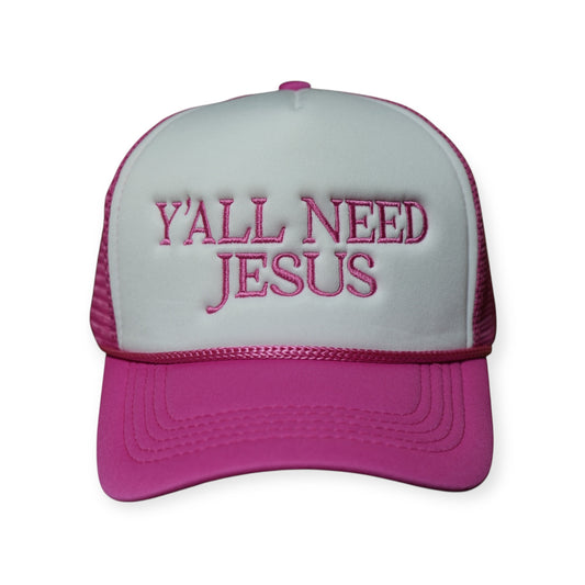 Pink and white polyester trucker hat with a curved brim and “Y’ALL NEED JESUS” embroidered across the front in pink thread.